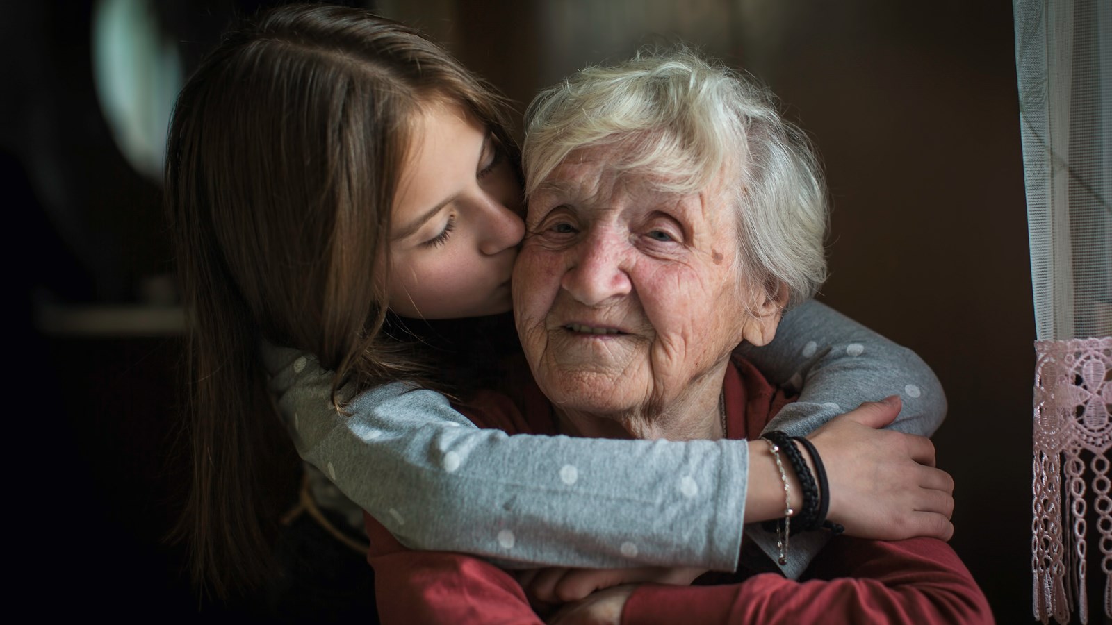 Mormor blir kramad och kysst bakifrån av sitt barnbarn